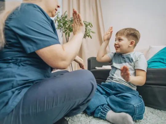 speech therapist engaging with young boy in nonverbal communication training, living room with warm decor, concept of education and cognitive skills development