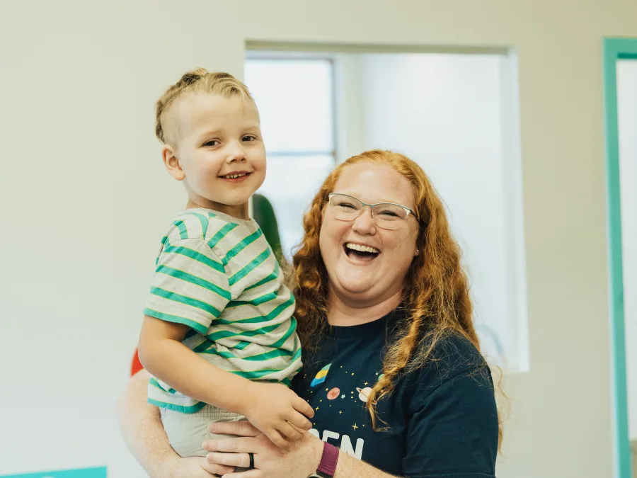 Child with autism held by RBT smiling